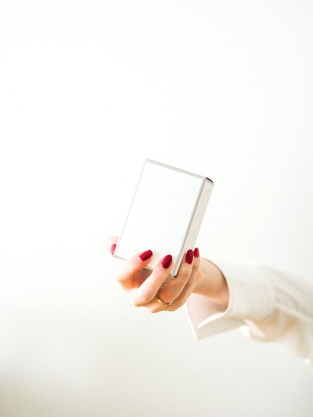 female hand holds perfume packaging without branding