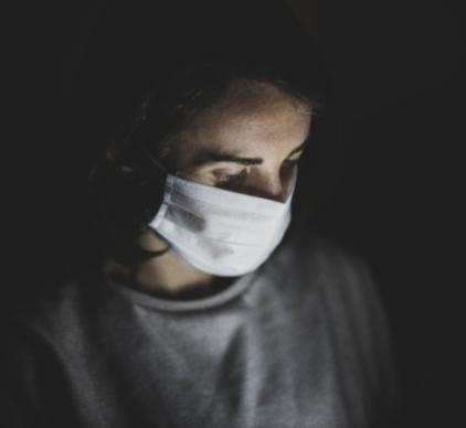 dark portrait of young woman wearing a mask